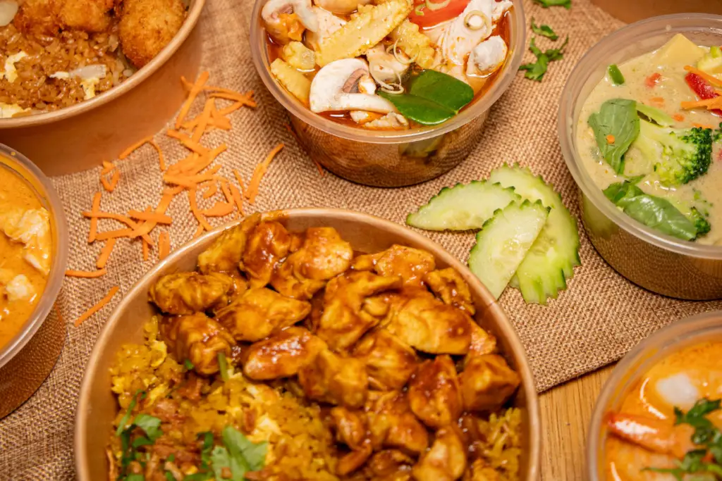 Assortiment de plats thaïlandais Bangcook : poulet satay, soupe Tom Yum, curry vert, curry rouge et curry massaman, spécialités street food thaï savoureuses