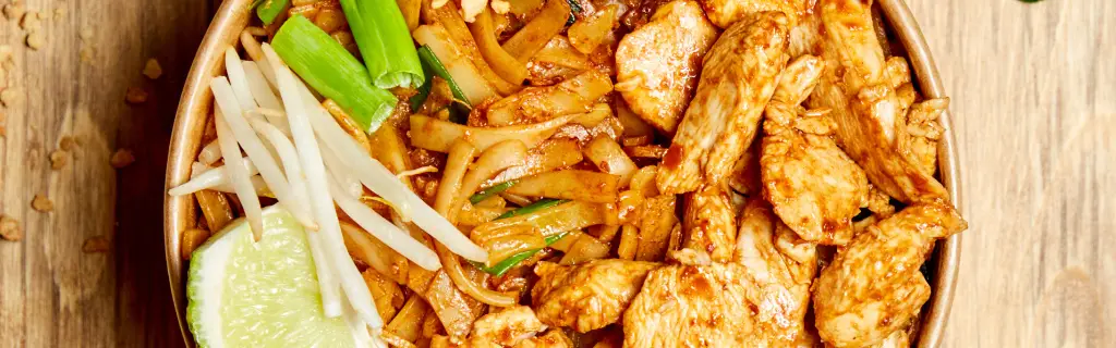 Pad Thaï poulet en gros plan : nouilles de riz, cacahuètes, citron vert